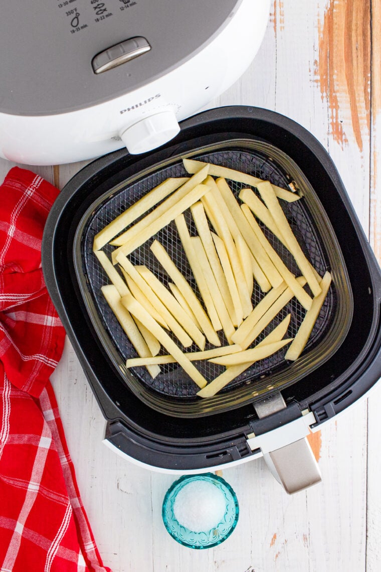 Shoestring fries coated in beef tallow arranged evenly inside an air fryer basket