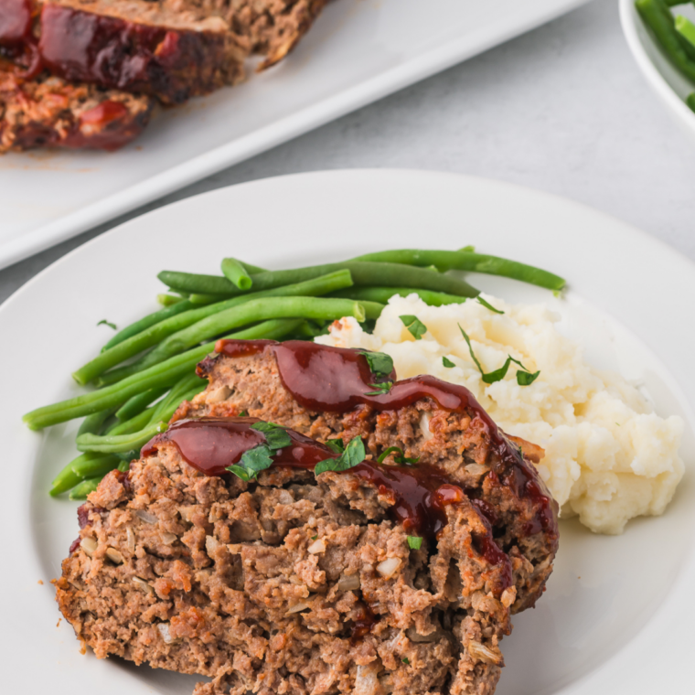 Plated slice of glazed meatloaf served with mashed potatoes and green beans for a classic Bob Evans style dinner
