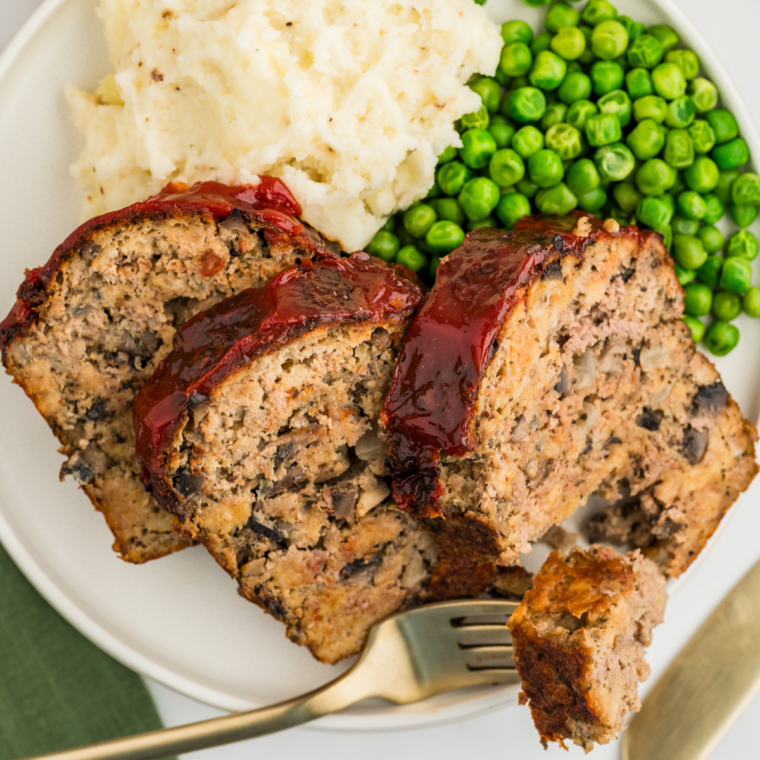 Sliced copycat Bob Evans meatloaf with a glossy caramelized signature glaze on a white serving platter