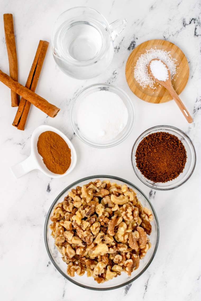 Raw almonds, raw cashews, egg white, granulated sugar, brown sugar, cinnamon, salt, and vanilla on a counter