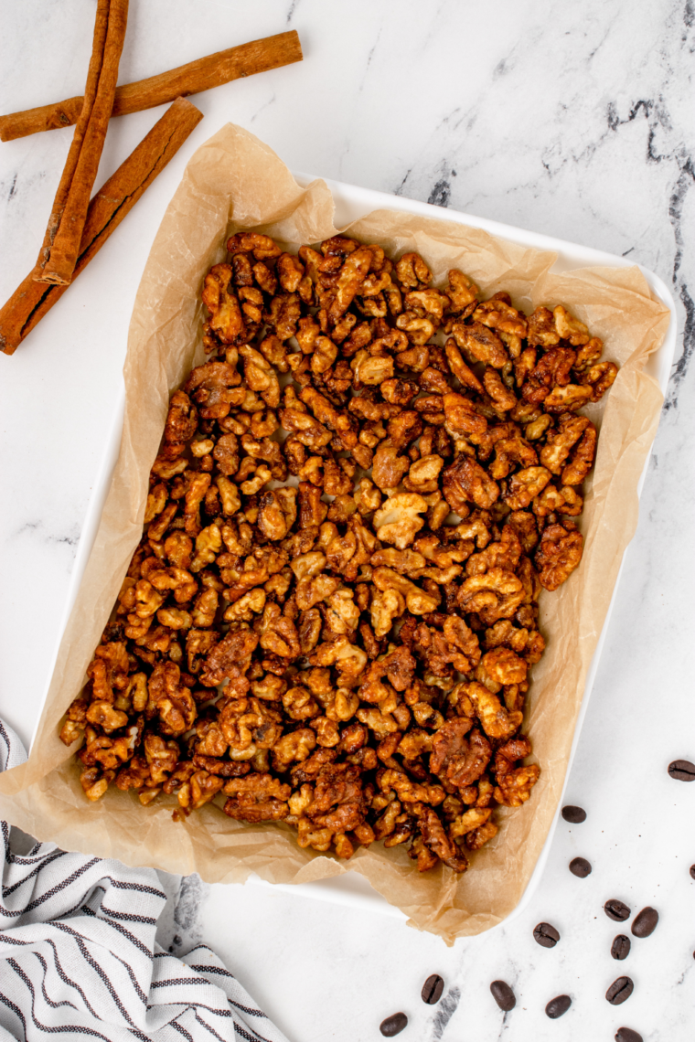 Cinnamon sugar candied walnuts spread in a single layer on a parchment-lined baking sheet