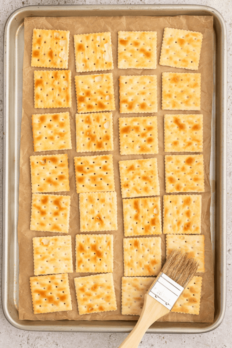 Pouring ranch seasoned oil over saltine crackers in a zip-top bag
