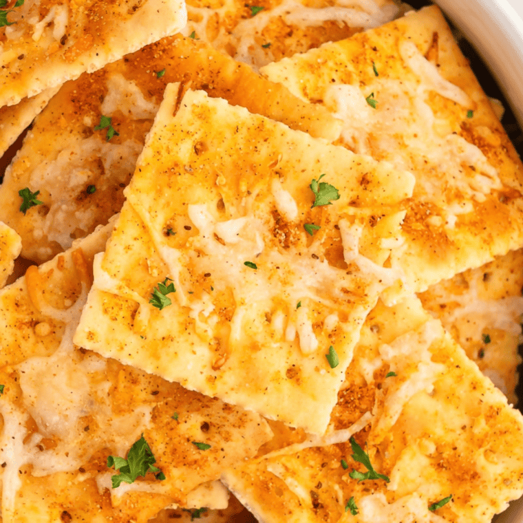 Copycat Buc-ee's Ranchin' Saltines piled on a wooden board with a small bowl of ranch seasoning