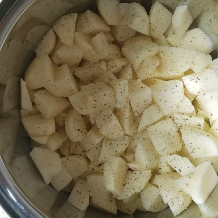 Peeled russet potato chunks, chicken broth, and salt in an Instant Pot inner pot before pressure cooking
