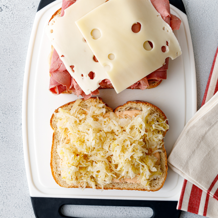 Assembling a Reuben with Swiss, corned beef, sauerkraut, and Thousand Island on buttered rye