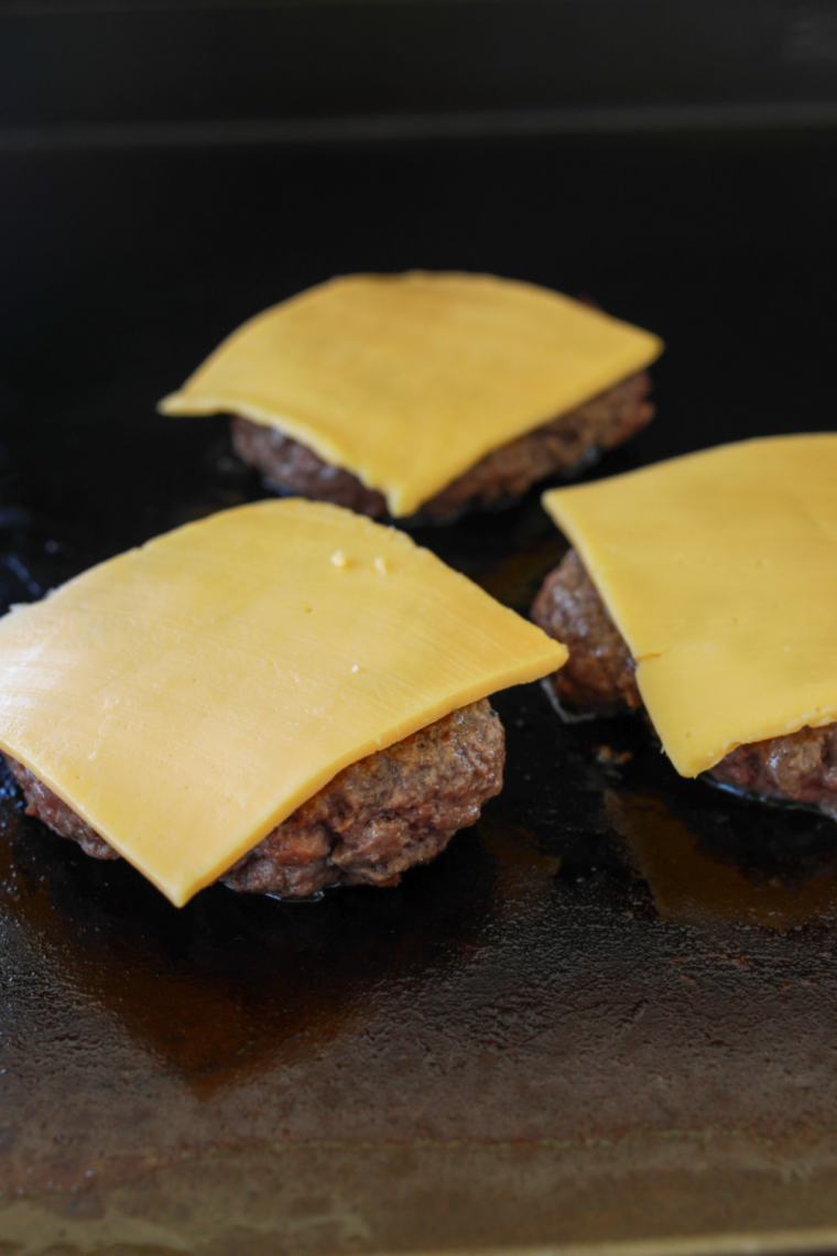 American cheese melting on thin steakburger patties