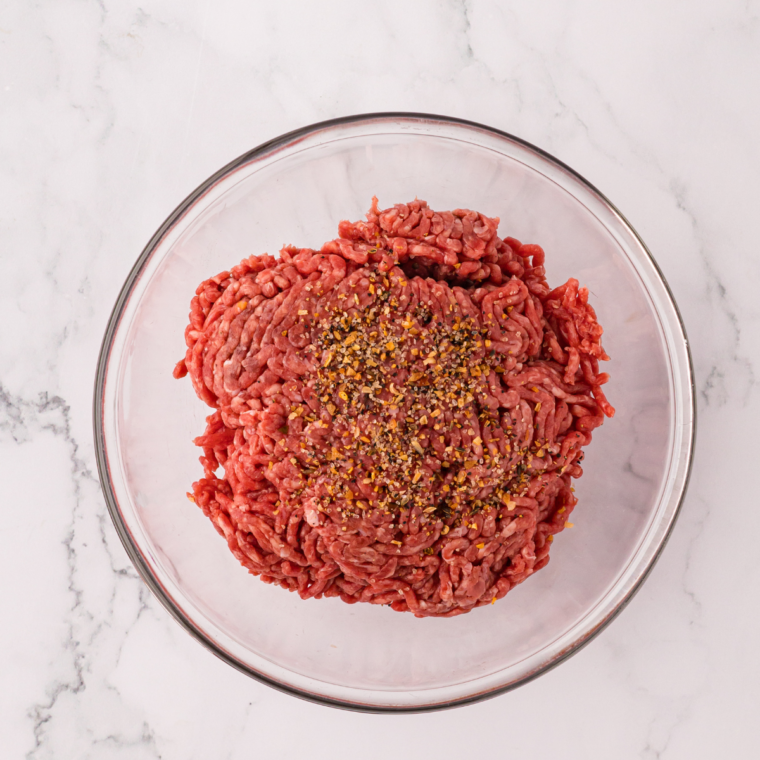 Salt, pepper, garlic powder, and onion powder mixed in a small bowl with the ground beef.