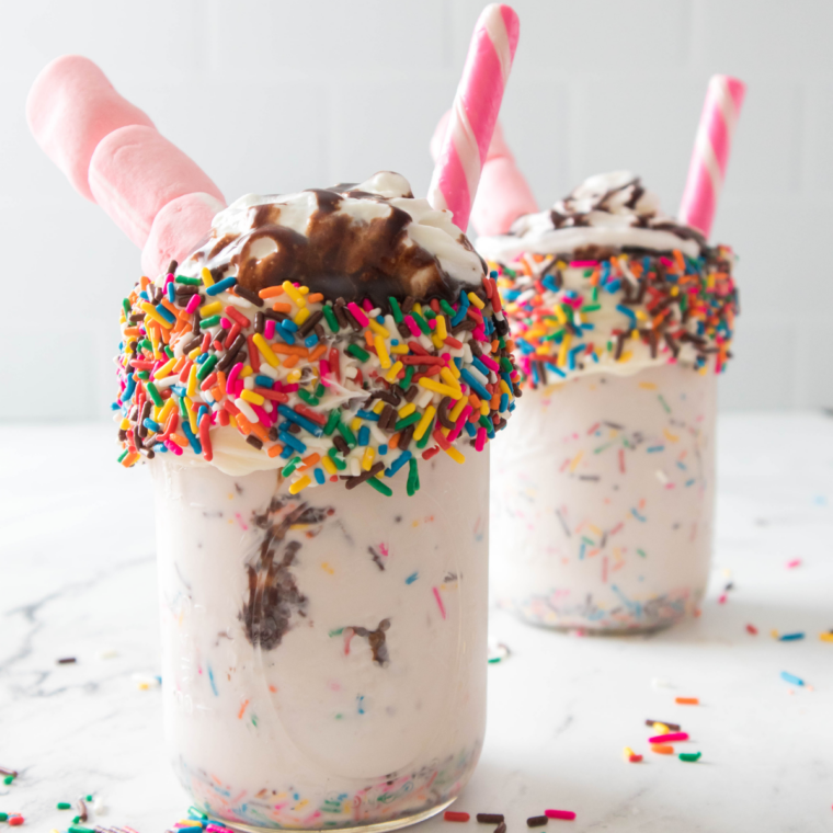 Ninja Creami Steak 'n Shake birthday cake shake topped with whipped cream, rainbow sprinkles, and a cherry