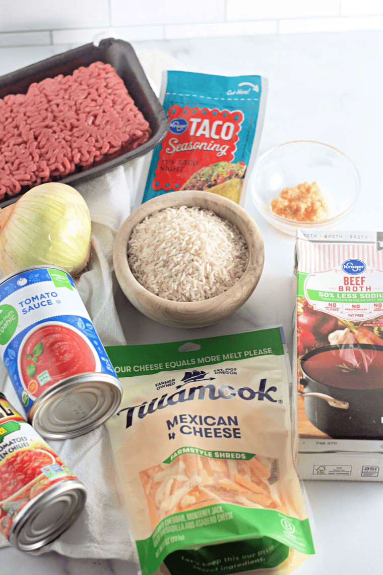 Taco rice skillet ingredients: ground beef, onion, garlic, taco seasoning, tomato sauce, Rotel, beef broth, rice, and cheese