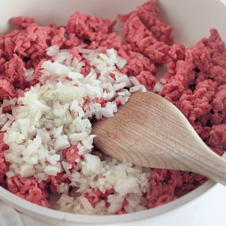 Lean ground beef and diced onion browning in a large skillet for taco rice