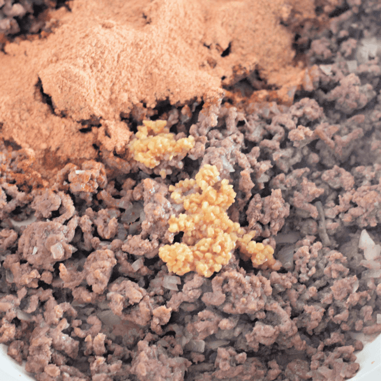 Taco seasoning and minced garlic stirred into browned ground beef in a skillet