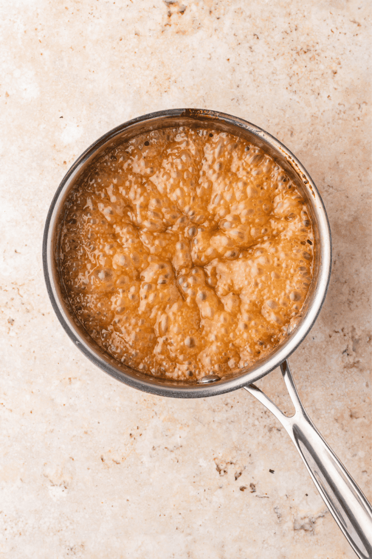 Butter, brown sugar, and corn syrup boiling in a saucepan for caramel