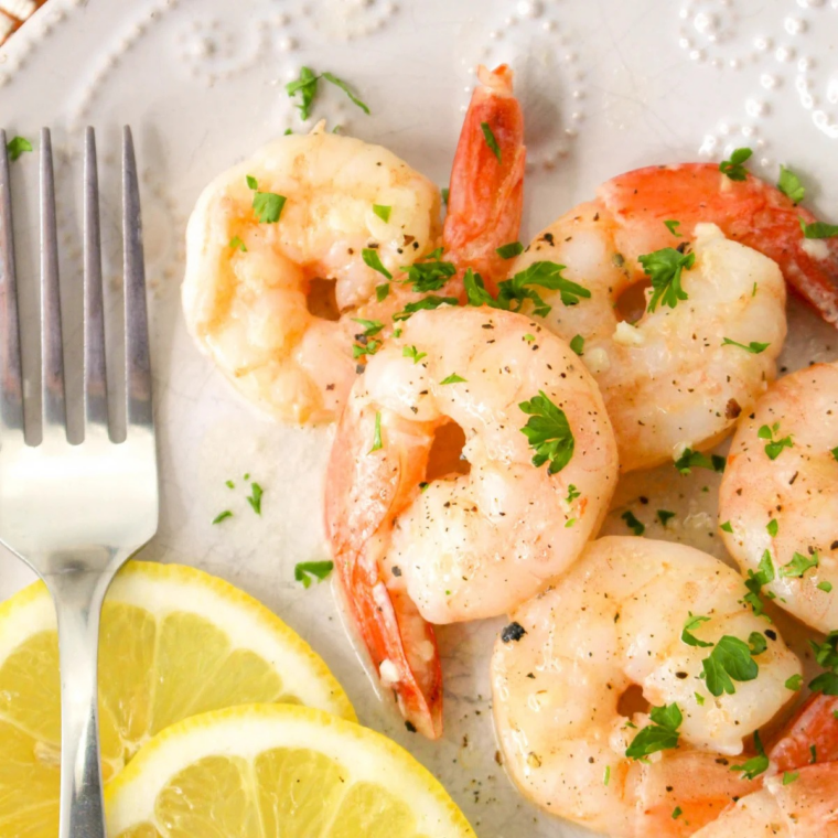 Garlic butter lemon shrimp marinade on juicy cooked shrimp with lemon slices and chopped parsley