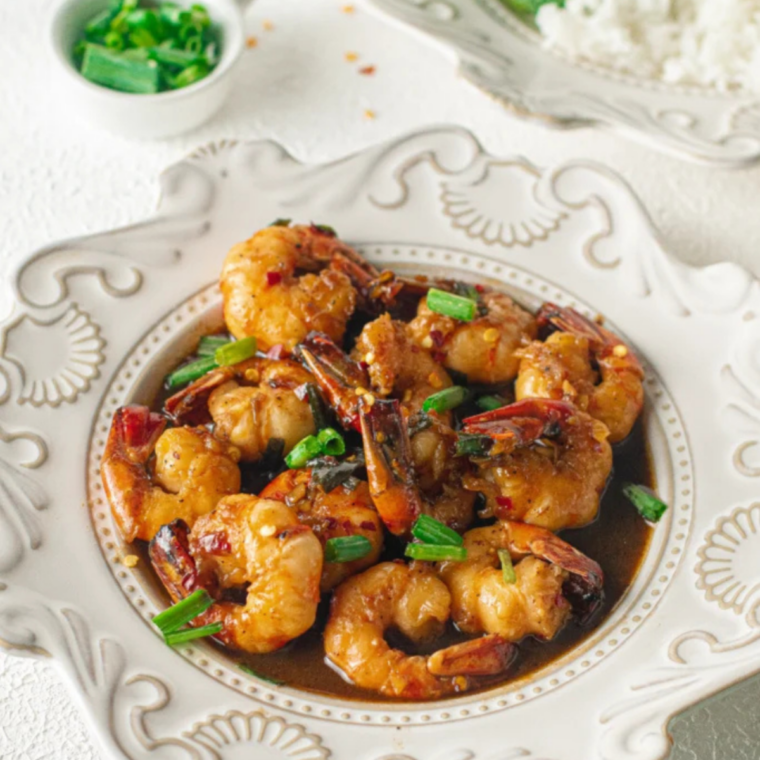 Sticky honey garlic shrimp marinade glazing shrimp topped with sesame seeds and sliced green onions