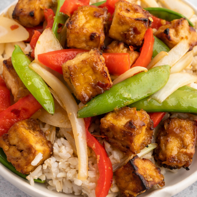 Sweet and spicy gochujang tofu marinade coating crispy red-glazed tofu cubes topped with sesame seeds and green onions