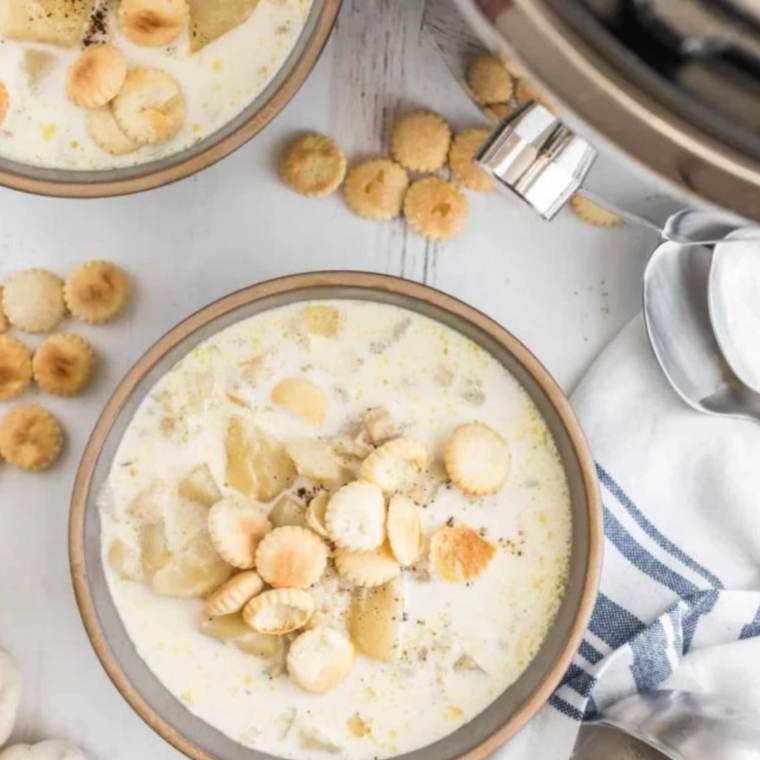 Ladle lifting thick clam chowder with potatoes and clams from the pot