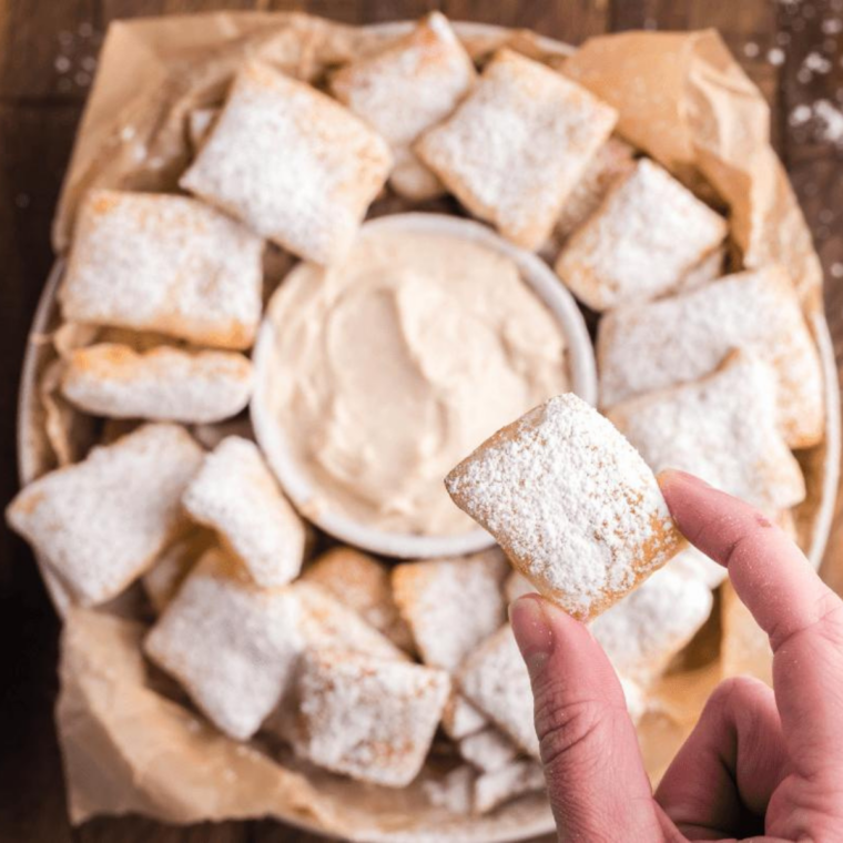 Copycat Auntie Anne's cream cheese dip in a white bowl with warm cinnamon sugar pretzel bites