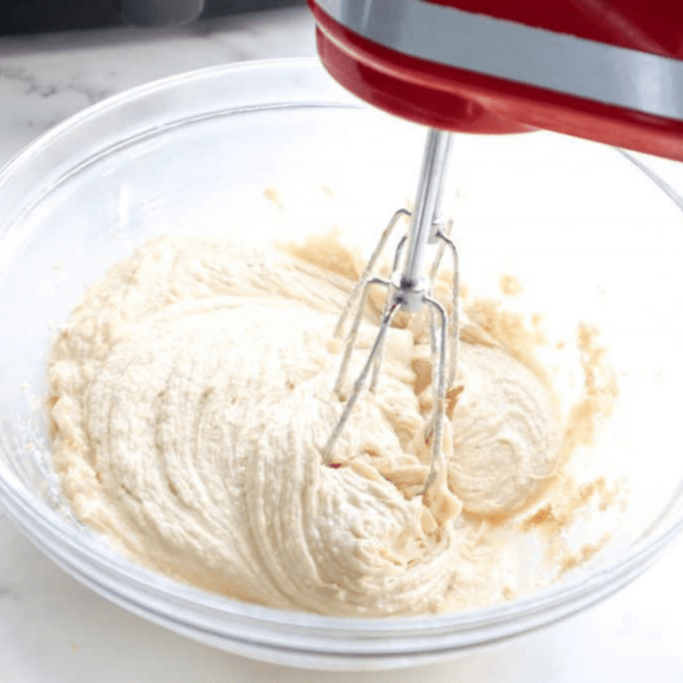 Hand mixer beating cream cheese and butter until smooth and fluffy for copycat Auntie Anne's dip