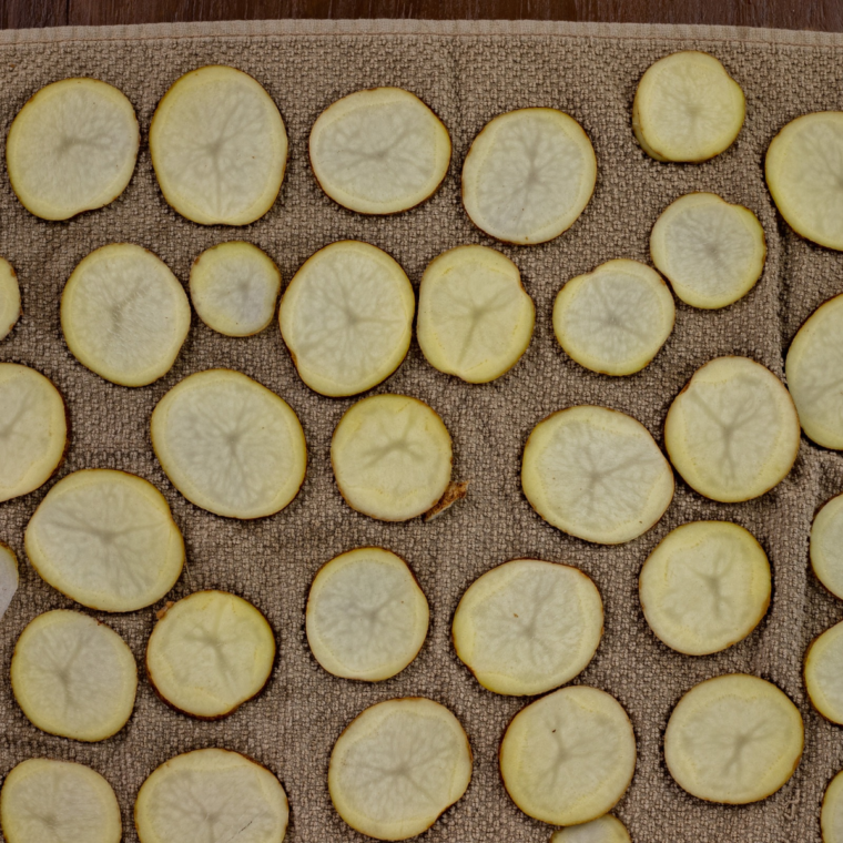 Soaked potato slices patted dry on a kitchen towel before air frying