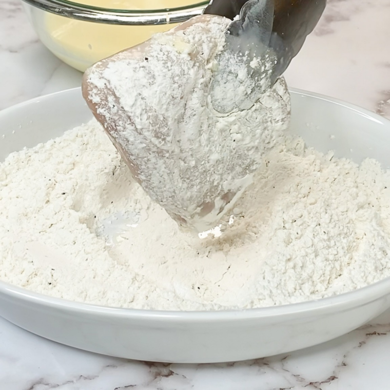 Double-dredged chicken cutlets with a thick, craggy flour coating resting on a plate