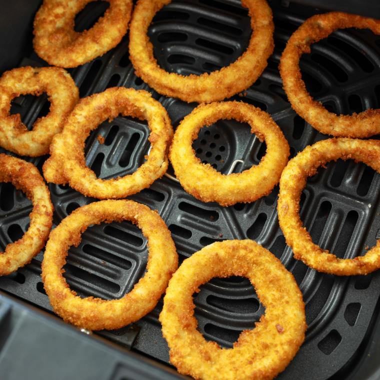 breaded onion rings in a single layer in an air fryer basket before cooking