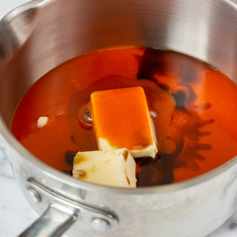 Pouring cayenne pepper hot sauce into melted butter in a saucepan