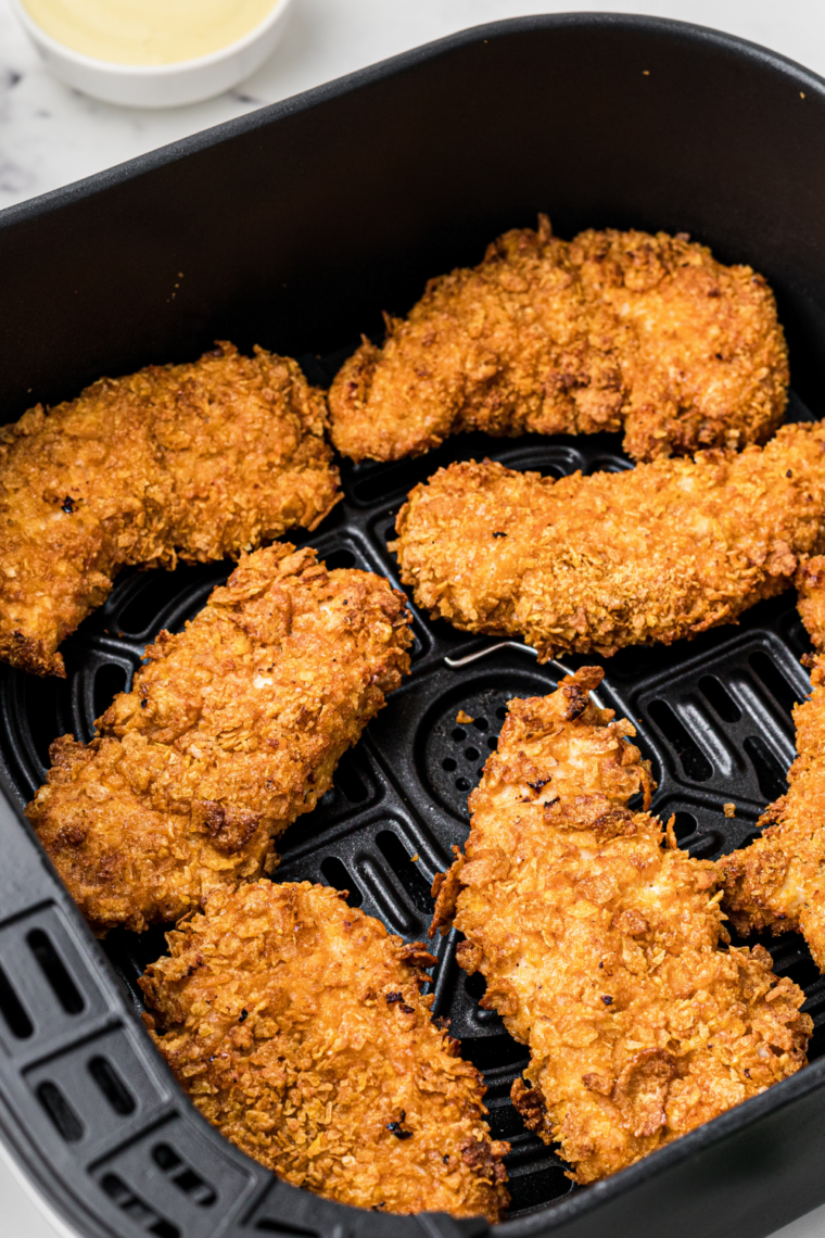 Golden air fryer Hardee&rsquo;s chicken tenders after flipping, crispy and browned