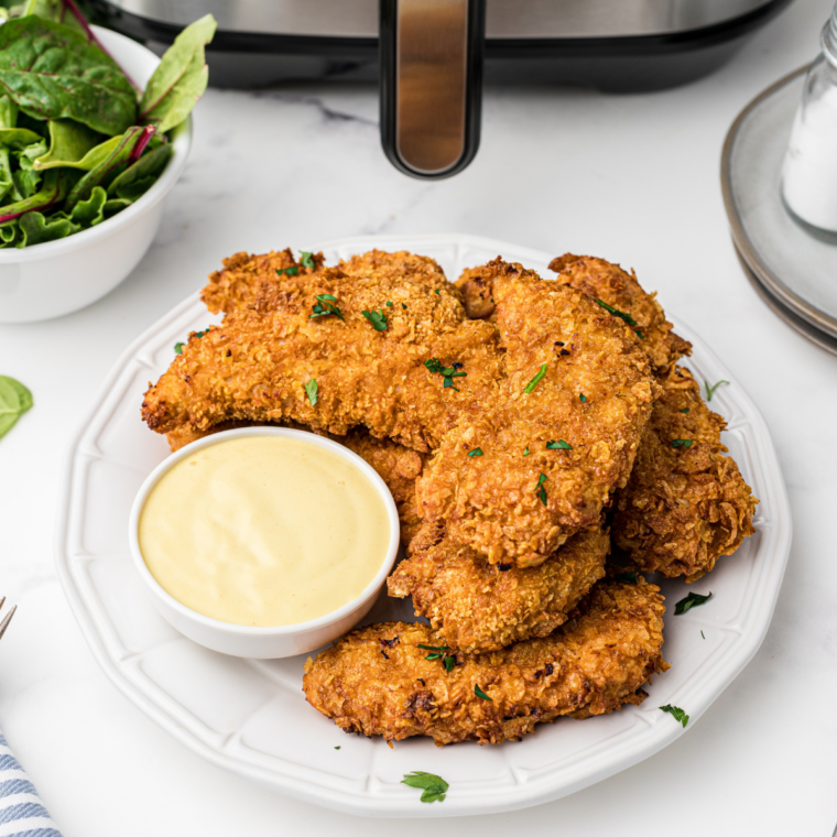Copycat Hardee&rsquo;s chicken tenders piled in a basket with honey mustard and ranch dipping cups