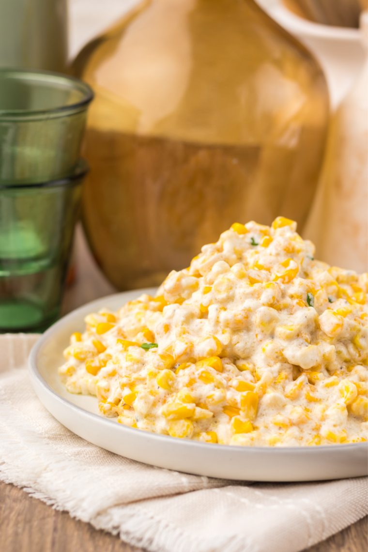 Plate of creamy slow cooker creamed corn served alongside sliced prime rib.