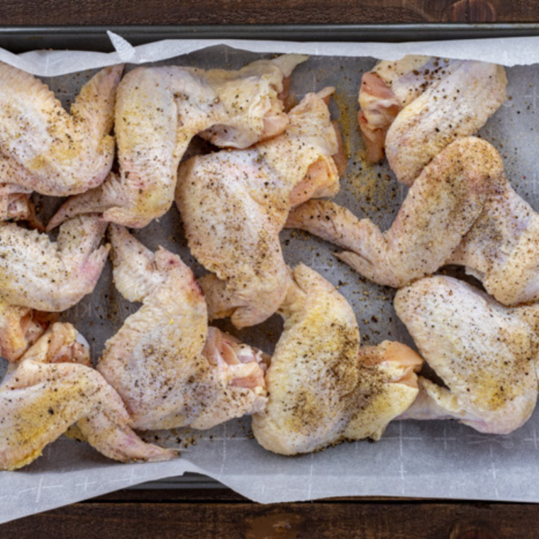 Chicken wings tossed with baking powder and seasonings in a large bowl.