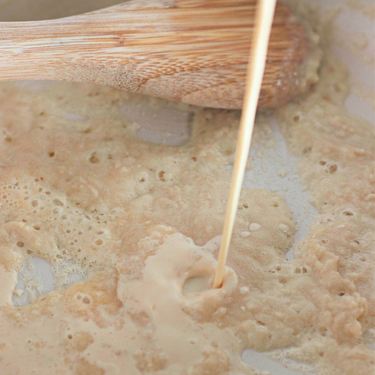 Butter and flour being whisked into a roux in a saucepan for homemade cheese sauce