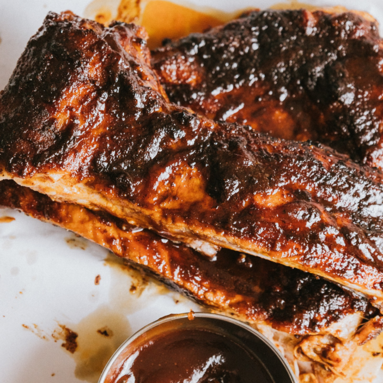 Bowl of homemade Kansas City BBQ sauce next to a rack of saucy glazed ribs