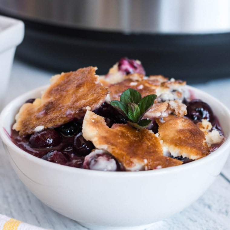 "Delicious Instant Pot Blueberry Cobbler topped with whipped cream and fresh blueberries"