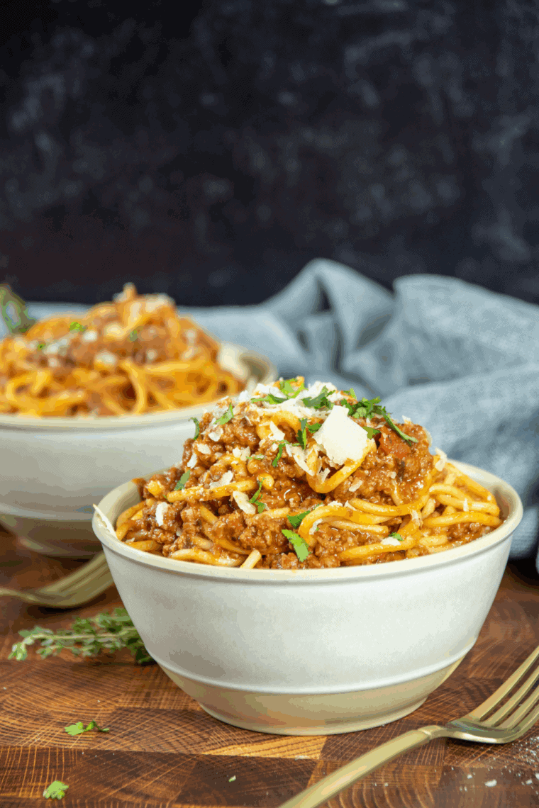 Bowl of rich Old Spaghetti Factory-style meat sauce over spaghetti noodles, garnished with fresh herbs.