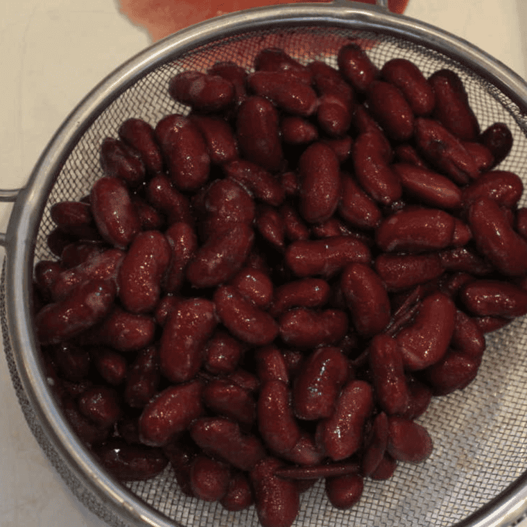 Mashed kidney beans in a mixing bowl, showing a creamy texture with a few chunks for added consistency.