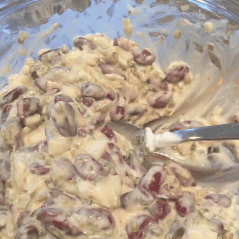 A bowl of creamy New England Bean Dip served with tortilla chips and fresh vegetables.