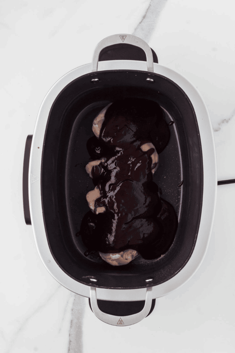 Pouring the blended barbecue sauce over the chicken, coating evenly.