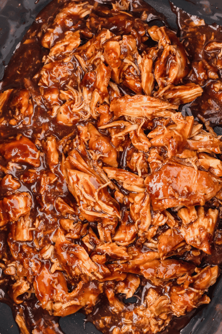 Crock Pot BBQ pulled chicken shredded in sauce inside slow cooker, ready to serve.