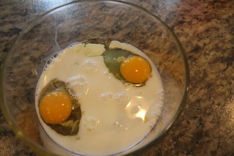 overhead process shot: two eggs in a bowl with milk to make air fried french toast