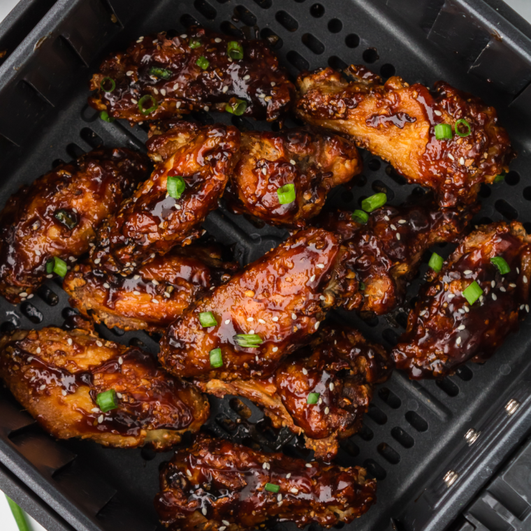 Air fryer Chinese chicken wings with a crispy, golden-brown coating served with sesame seeds and green onions.