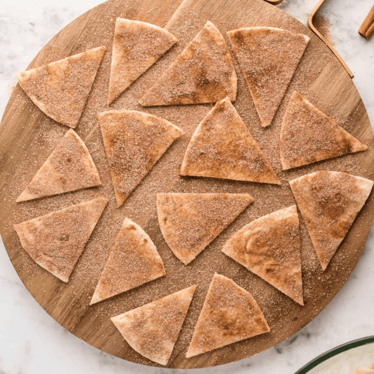 Tortilla pieces being brushed with melted butter and sprinkled with a cinnamon sugar mixture for a delicious snack.