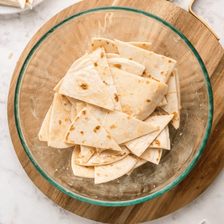 Brushing tortilla pieces with melted butter and sprinkling with a cinnamon sugar mixture for a sweet, crispy treat.