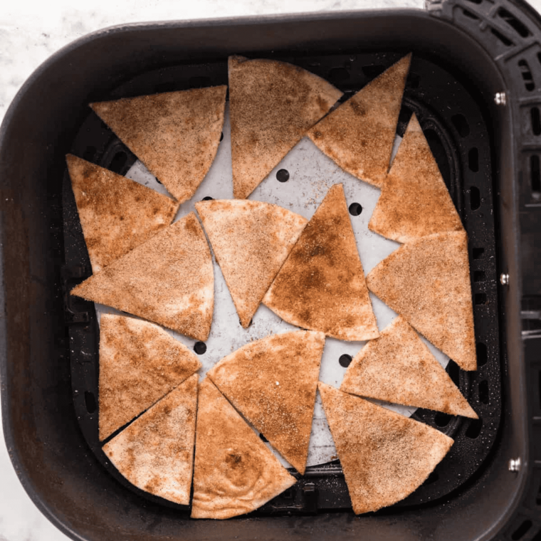 Coated tortilla wedges arranged in a single layer in the air fryer basket, ready to cook to golden perfection.