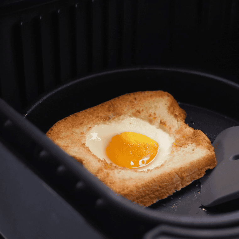 Cracking an egg into the bread hole and air frying at 330°F until the egg is perfectly cooked to your preference.