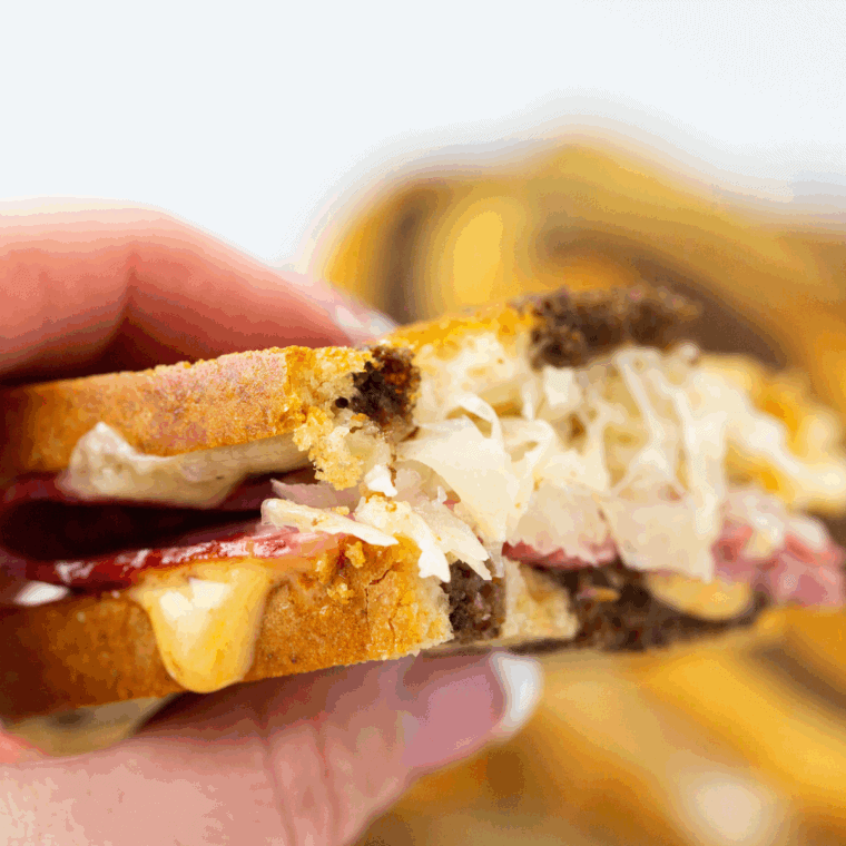Air fryer Reuben sandwich with golden toasted bread, melted Swiss cheese, corned beef, sauerkraut, and Russian dressing, served on a plate.