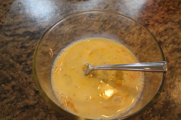 overhead process shot: beaten eggs and milk in a bowl with a fork to make french toast in air fryer