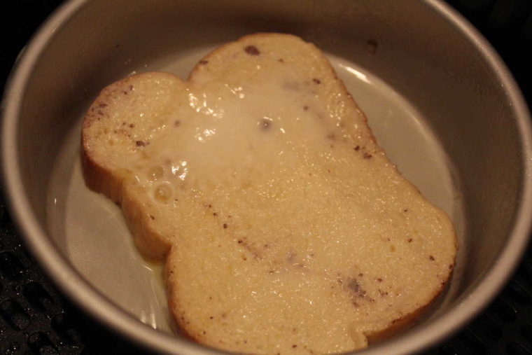 overhead process shot: a piece of air fryer french toast in the pan before air frying