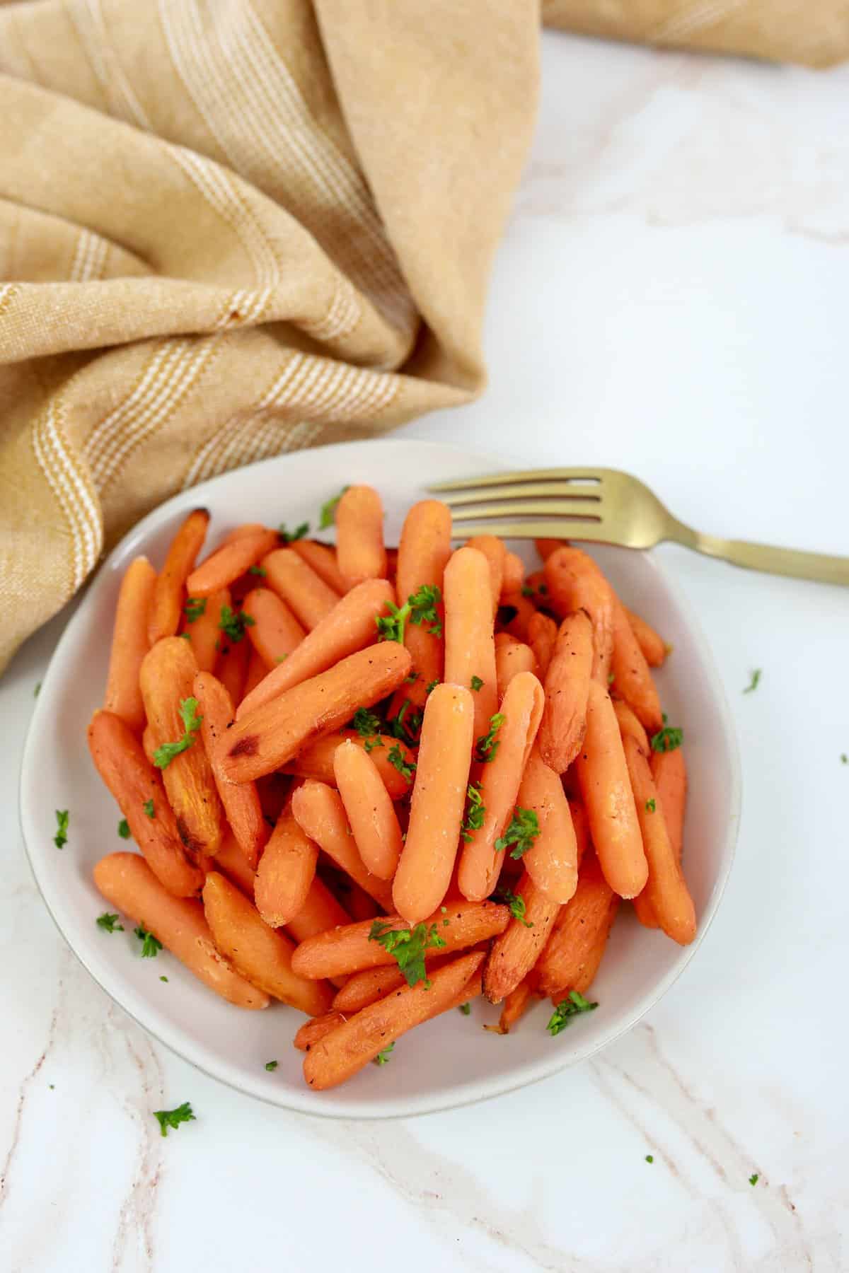 Air Fryer Honey Carrots on a white plate with a gold fork and a white background