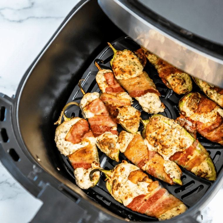 Crispy air fryer bacon wrapped jalapeno poppers resting on a plate before serving