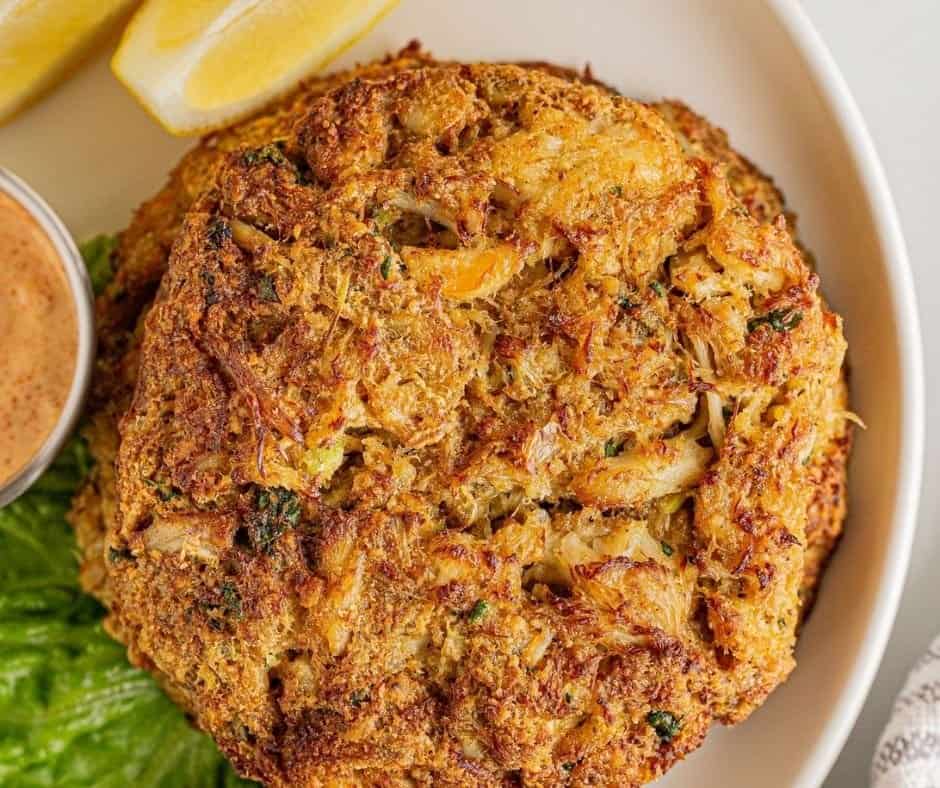 Garnishing air-fried crab cakes with fresh herbs and dipping sauce.